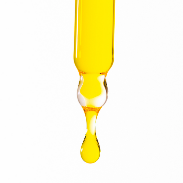 Yellow dropper with a drop of liquid on a white background