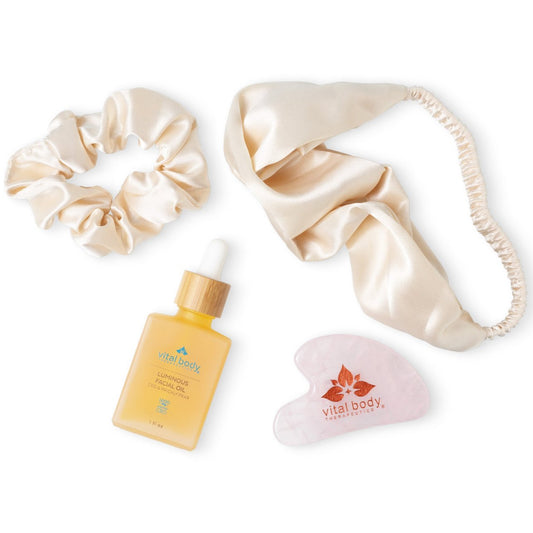 Beauty product set with a scrunchie, face mask, bottle, and heart-shaped item on a white background.