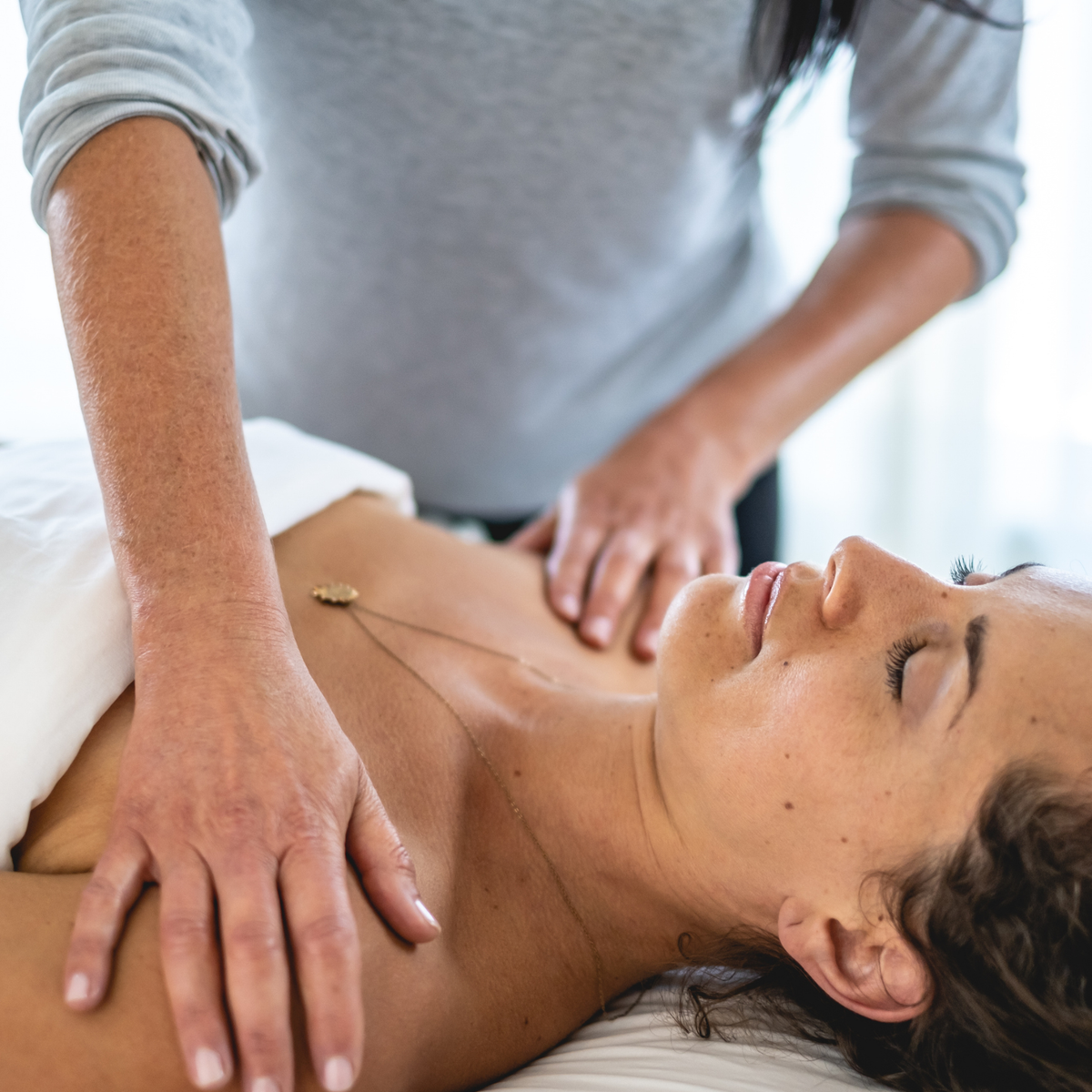 Person receiving a massage from another person in a clinical setting.