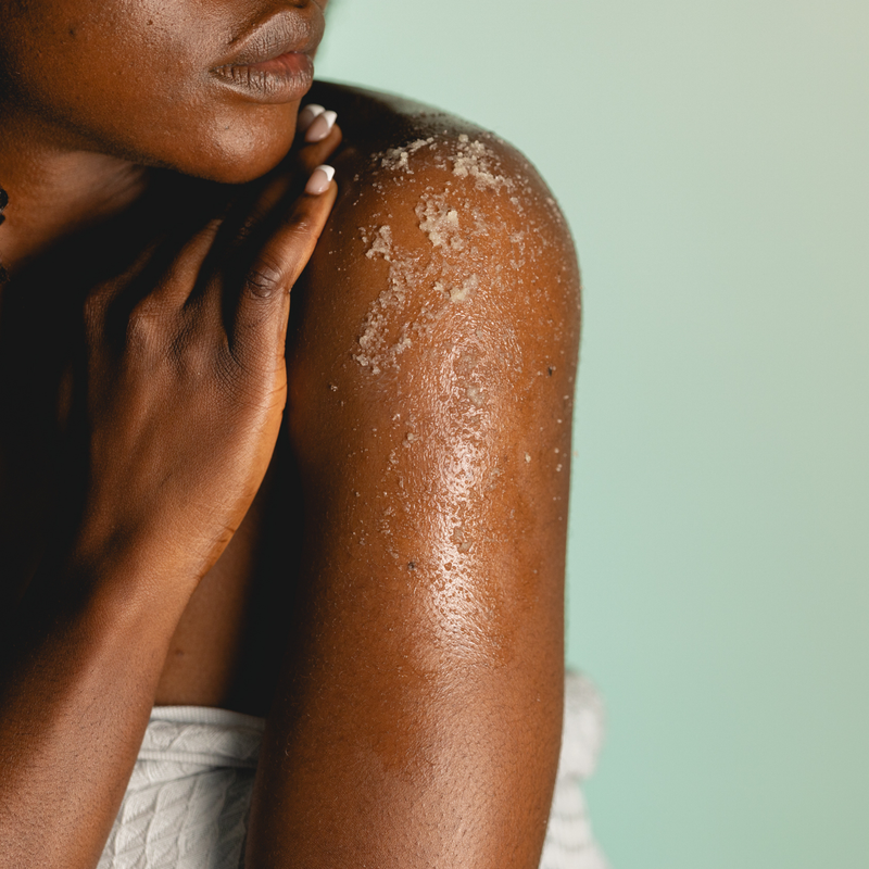 Person with a close-up of their shoulder and arm against a light green background