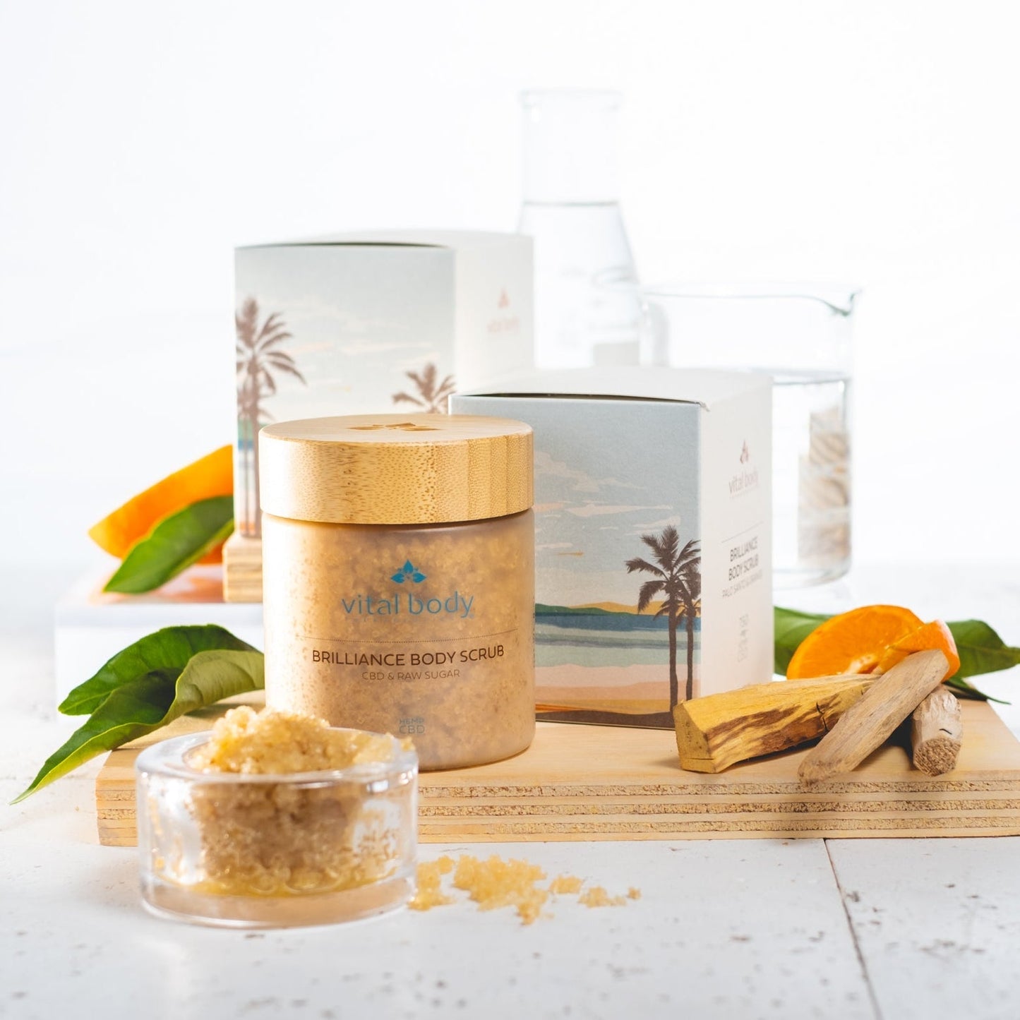 Vital Body Brilliance Body Scrub with packaging and ingredients on a white background