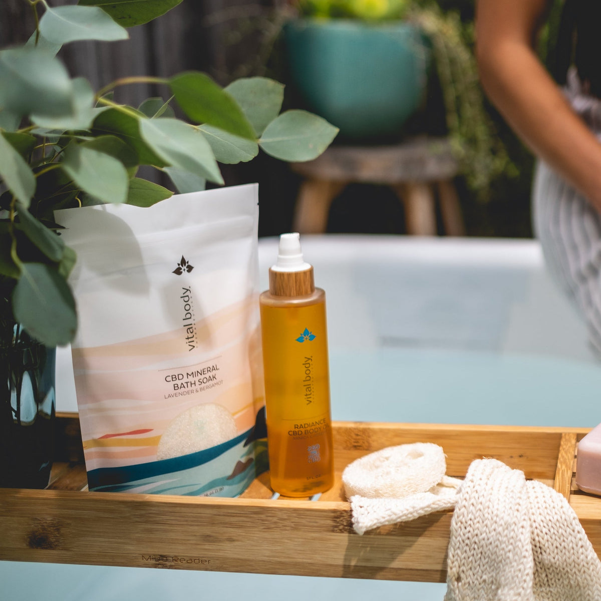 CBD mineral bath foam and oil on a wooden tray with a blurred background