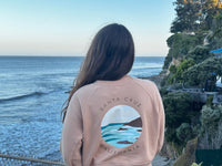Person wearing a pink sweatshirt with a graphic design of Santa Cruz, California, overlooking the ocean.