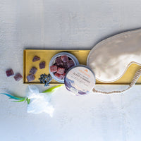 Sleep aid products including gummies, a container of gummies, and a sleep mask on a light surface.