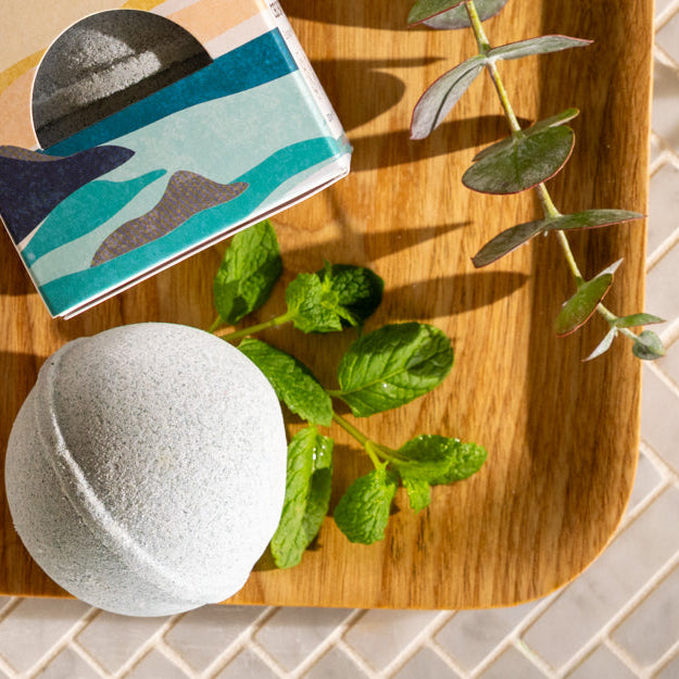 Bath bomb on a wooden board with a book and eucalyptus leaves