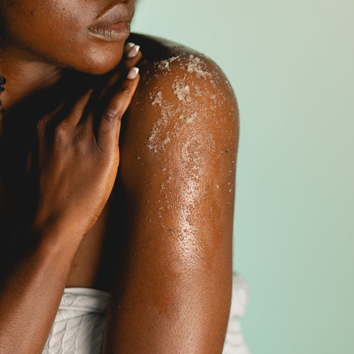 Person with visible skin condition on arm against a light green background