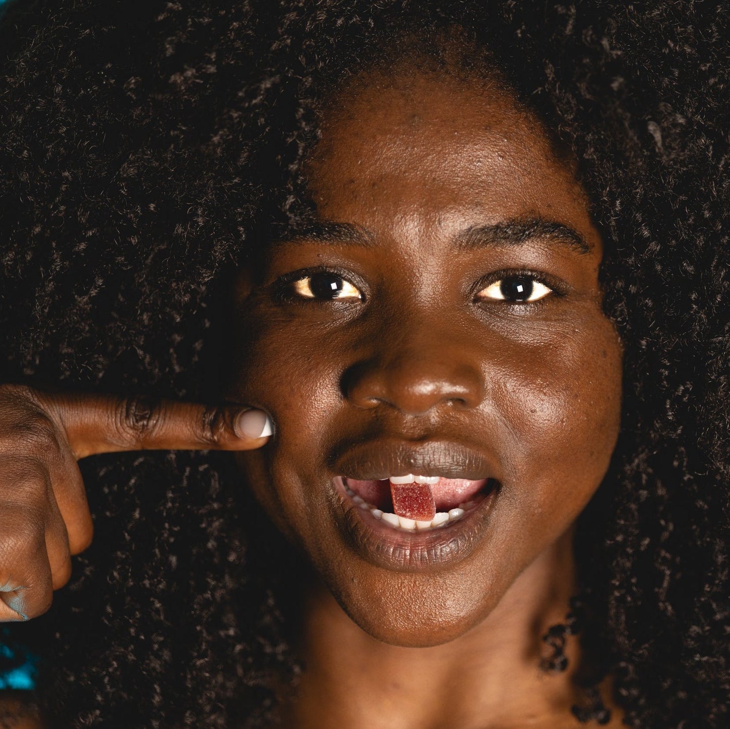 Person with a finger pointing to their eye against a dark background
