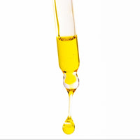 Yellow liquid being dripped from a pipette onto a white background
