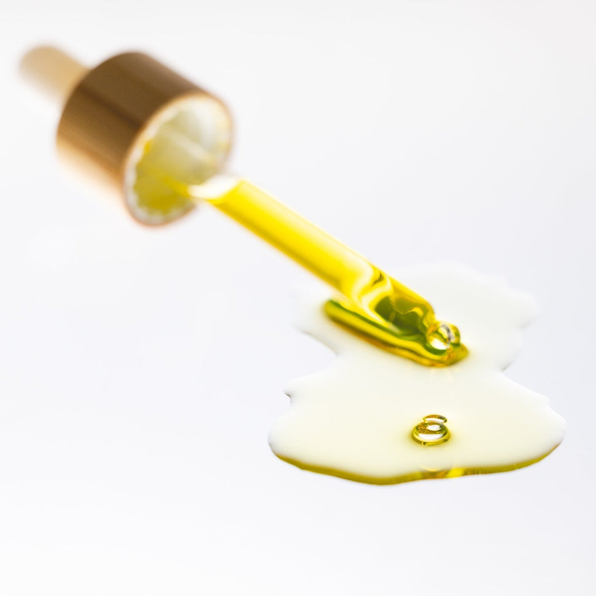 Gold dropper with yellow liquid on a white background
