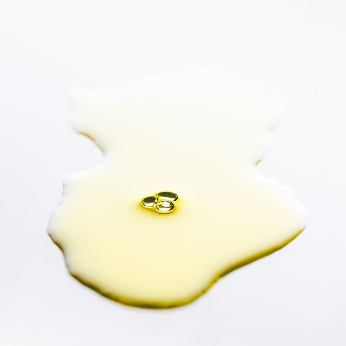 Pool of golden oil on a white background
