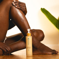 Person applying aftershave body cream to their leg with a bottle of the product in front.