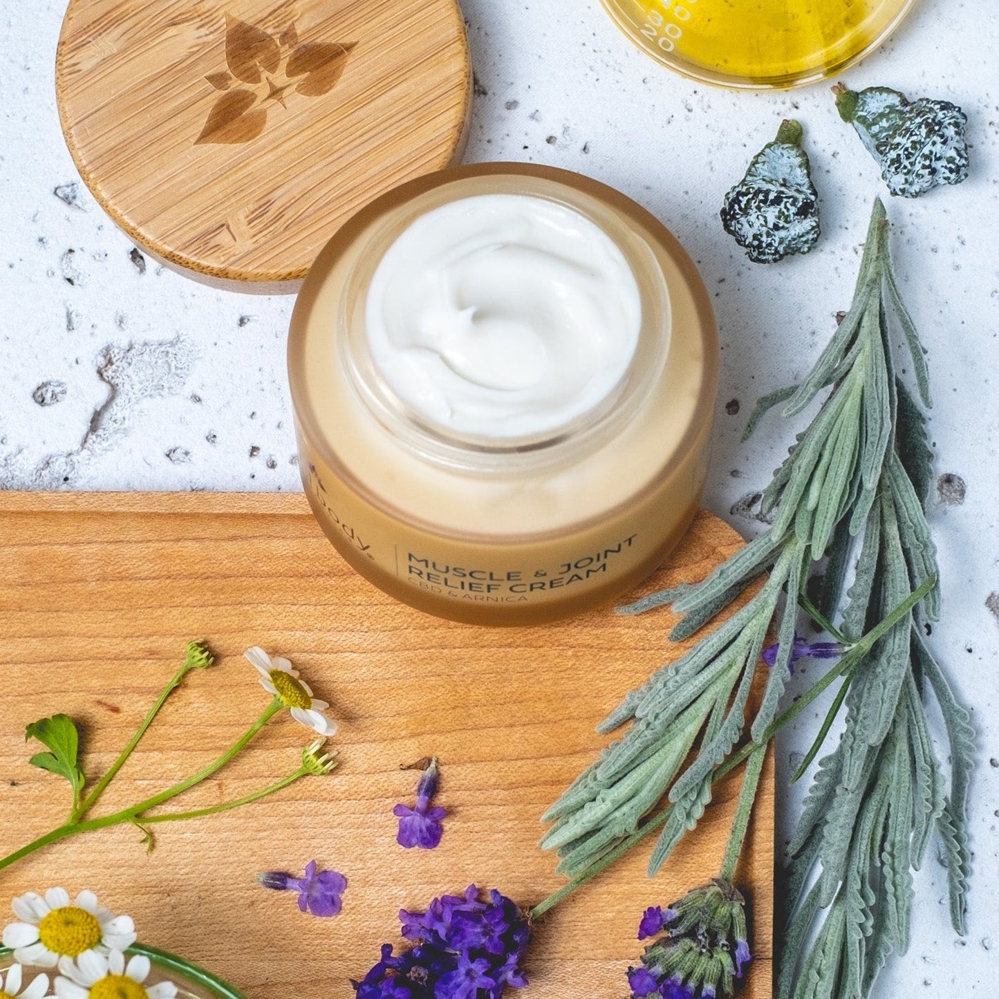 Jar of cream on a wooden board with herbs and flowers