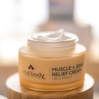 Jar of Muscle & Joint Relief Cream with 'vital body' branding on a wooden surface.