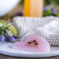 Heart-shaped tool with 'vital body' logo on a white surface with blurred background