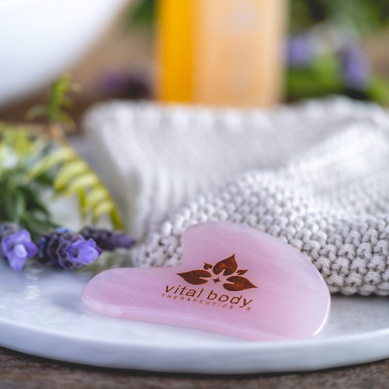 Pink heart-shaped tool with 'vital body' branding on a white surface with blurred background