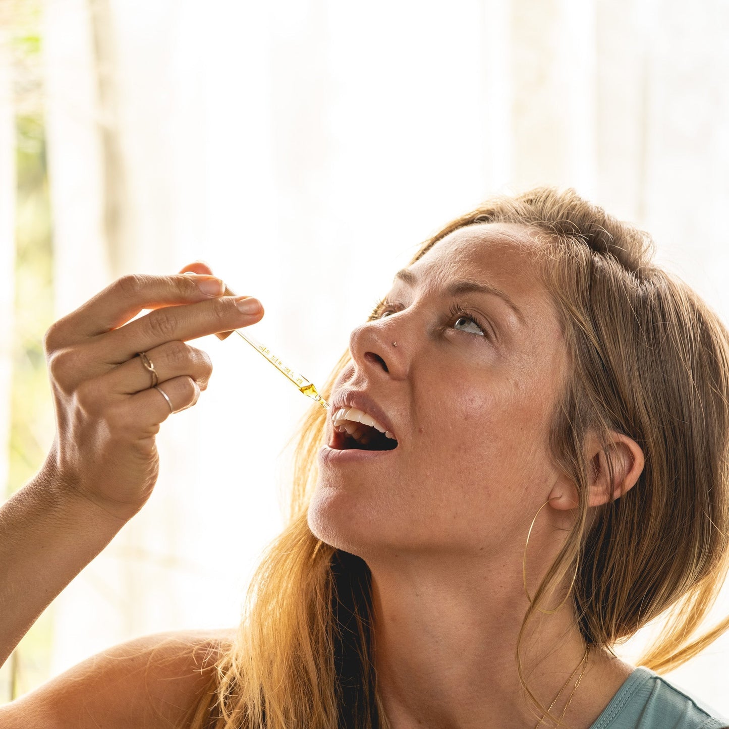 Woman taking a pill with a dropper in a bright room