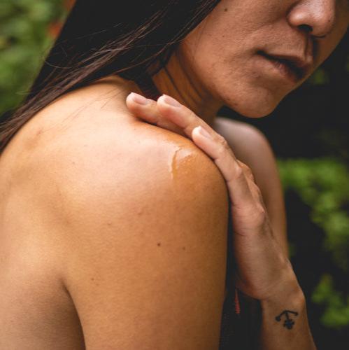 Person with a small amount of liquid on their shoulder against a blurred natural background