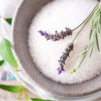 Bowl of lavender sugar with lavender flowers and green leaves on a light background